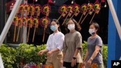 戴着口罩的行人走过北京街头一个售卖传统风车玩具的商铺。(2022年9月13日)