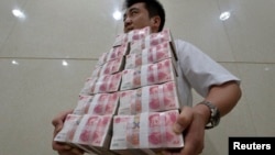 中国山西太原一家银行职员手捧成捆的人民币百元现钞。(资料照片)