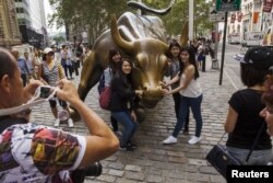 资料照:中国游客在纽约华尔街的铜牛前合影。(2015年8月24日)