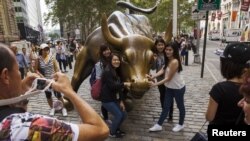 资料照:中国游客在纽约华尔街的铜牛前合影。(2015年8月24日)