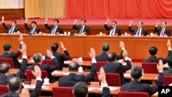 2021年11月11日,中共第19届中央委员会第六次全体会议上,政治局常委们举手表决。从左向右依次是韩正、王沪宁、栗战书、习近平、李克强、汪洋和赵乐际。照片由新华社发表,美联社提供。