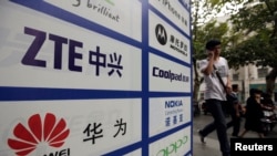 资料照片:一名中国男子从武汉街头有着华为和中兴标徽的广告牌前走过。(2012年10月11日)