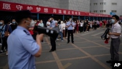 中国高考第一天,北京一处考场外警察和学校教师使用扩音器要求在外等候的考生家长遵守秩序。(2022月6月7日)