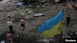 在俄罗斯进行的一次袭击之后,人们在乌克兰哈尔科夫郊外查看一处被毁坏的木仓库。(2022年6月3日)