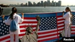 资料照:两名华人女子在纽约手举自由女神像与美国国旗的横幅。
