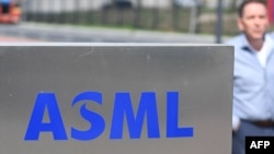 资料照:一名员工走过世界最大半导体制造机器供应商、位于费尔德霍芬的荷兰阿斯麦公司(ASML)总部的标识。(2018 年4月17日)