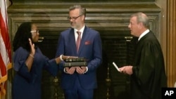 凯坦吉·布朗·杰克逊在美国最高法院首席大法官罗伯茨的主持和丈夫帕特里克·杰克逊医生的注视下宣誓就任大法官。(2022年6月30日)