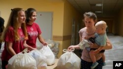 乌克兰东部顿涅茨克地区一名妇女带着孩子在领取当地政府提供的援助物资(2022年6月14日)