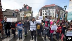 Một người tổ chức dẫn đầu những em nhỏ cầm biểu ngữ đi khỏi khu Molenbeek trong cuộc tuần hành ở Brussels, ngày 17 tháng 4, 2016.
