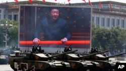 参加北京大阅兵的中国坦克部队在显示国家主席习近平的大屏幕前通过。(2015年9月3日)