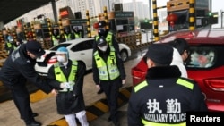 戴着面具的警察在武汉咸宁的高速缴费站检查汽车里是否载有偷运的野生动物。(2020年1月24日)