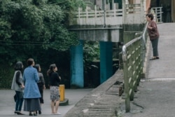 饰演秀英阿嬷的陈淑芳(右)向穿着青蓝色大衣的死去丈夫的情人(丁宁饰)喊了一声:“蔡小姐!”(威视电影授权提供)