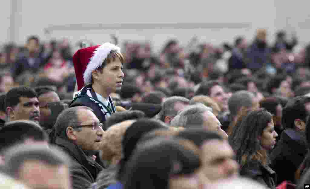 A boy listens to Pope Francis delivering his "Urbi et Orbi" (to the City and to the World) message in St. Peter's Square at the Vatican, Dec. 25, 2014.