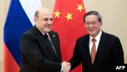 在俄罗斯卫星通讯社发布的这张合影中,俄罗斯总理米哈伊尔·米舒斯京(左)和中国总理李强在伊斯兰堡举行的上海合作组织峰会期间会晤前握手。