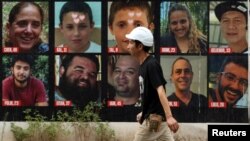 以色列特拉维夫一名男子走在10月7日哈马斯致命袭击中被绑架的人质海报前,下排左一为以色列裔美国人赫什·戈德堡-波林。(路透社:2024年9月1日)