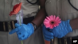 6月26日,印度孟买亚洲最大的贫民窟一个免费的医疗营关闭时,保安人员手持人们为表达谢意而送给他们的花。