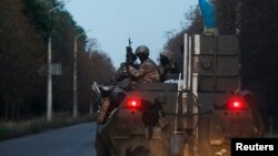 乌克兰政府军士兵坐在装甲车顶前往乌东一处军事基地。(2014年8月19日)