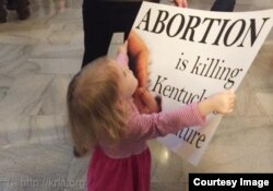 一个小孩子手举“堕胎是杀人”的标语牌 (图片来源:Kentucky Right to Life Association)