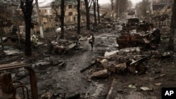 На цьому архівному фото жінка йде серед знищених російських танків у Бучі у неділю, 3 квітня 2022 р. (Фото: AP Photo/ Rodrigo Abd)