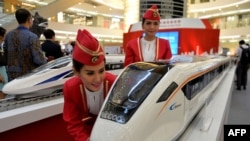 资料照:印度尼西亚几名模特在雅加达一家商场观看中国制造高铁模型。(2015年8月13日)
