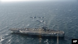 Ảnh chụp ngày 10/11/2017 do Lực Lượng Phòng vệ Nhật cung cấp. Hai chiến đấu cơ F/A-18 của Mỹ và chiến đấu cơ F-15 của Nhật bay bên trên tàu chiến USS Ronald Reagan tới một địa điểm tập trận không được tiết lộ.