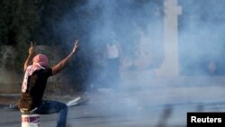 西岸城市拉马拉一名巴勒斯坦抗议者坐在用来盖住以色列催泪弹的桶上。(2015年10月15日)