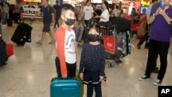 资料照:戴着口罩的儿童从武汉抵达悉尼机场。(2020年1月23日)