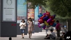 2013年6月26日,一位摊贩坐在北京街头人行道上贩卖气球。