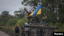 在刚从俄军手中收复的乌克兰东北部哈尔科夫州伊久姆镇,乌克兰军人站在竖着乌克兰国旗的BMP-1步兵战车上。(2022年9月14日)