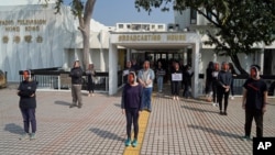 香港电台的员工头戴新闻主播利君雅的面罩在广播大楼外进行静默抗议。(2021年1月28日)