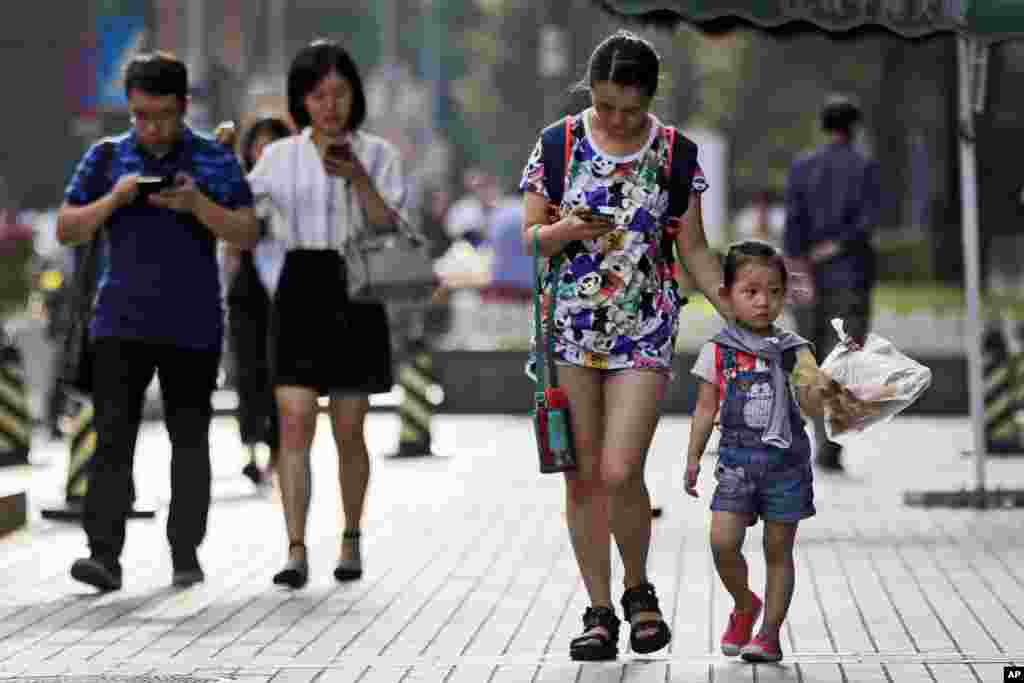 行人在在北京走过人行道时,看着他们的智能手机。随着手机在中国所有年龄组中越来越受欢迎,中国已经成为世界上最大的手机市场之一。(2017年8月9日)
