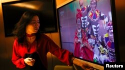 资料照片: 一名女子在北京一家海底捞餐厅和家人吃年夜饭时观看央视春节晚会(2021年2月11日)
