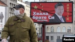 塞尔维亚一名戴着口罩的男子走过贝尔格莱德街头树立的感谢中国领导人习近平的广告牌旁。(2020年4月1日)