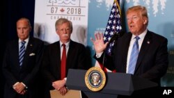 川普总统在加拿大魁北克省举行的G7峰会的新闻发布会上讲话。白宫首席经济顾问库德洛和国家安全顾问博尔顿在旁边(2018年6月9日)