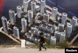 人走过天津滨海新区一处新居民楼群的墙壁(2015年10月18日)