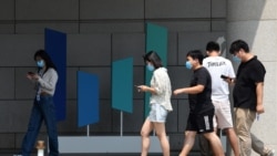 北京字节跳动总部大楼旁几个青年边走路边看手机。(2020年7月6日)