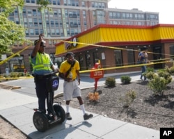 A Washington Metro Police officer raises police tape for a pedestrian to walk under following a shooting at 3800 block Georgia Ave., N.W., in the Petworth neighborhood of Washington, Sept. 7, 2016.