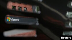 FILE - A bench frames a sign outside the Microsoft office in Cambridge, Massachusetts, U.S.