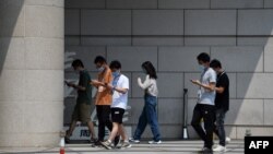 北京一群青年边走路边看手机。(2020年7月6日)
