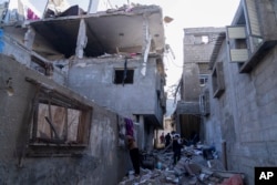 以色列空袭加沙地带的汗尤尼斯市后,巴勒斯坦居民在观看一座被炸毁的建筑物。(2023年12月3日)