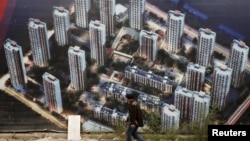 有人走过天津滨海新区一处新居民楼群的墙壁(2015年10月18日)