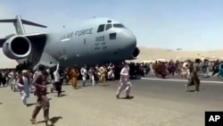 美国空军C-7运输机在喀布尔国际机场起飞时上百人在跑道上跟随奔跑。(2021年8月16日)