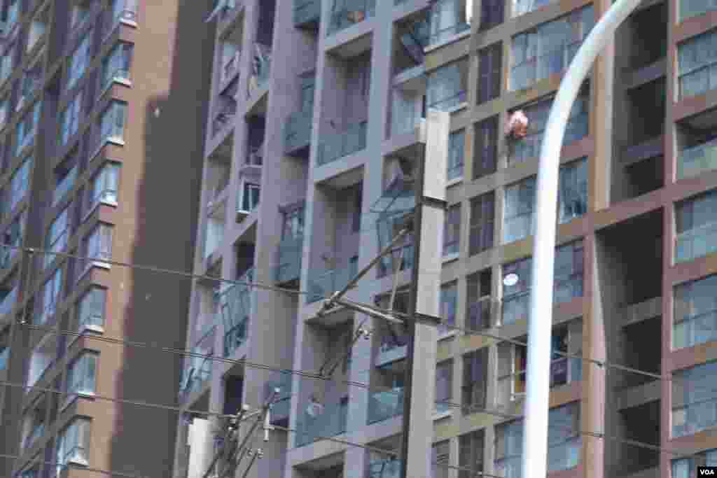 天津爆炸事故现场,核心爆炸区周围多座居民楼窗户被震碎,高速公路桥梁受损,多辆大货车被炸翻,小汽车起火或被砸,多名当地居民仍逗留在事故现场。(美国之音记者东方拍摄)