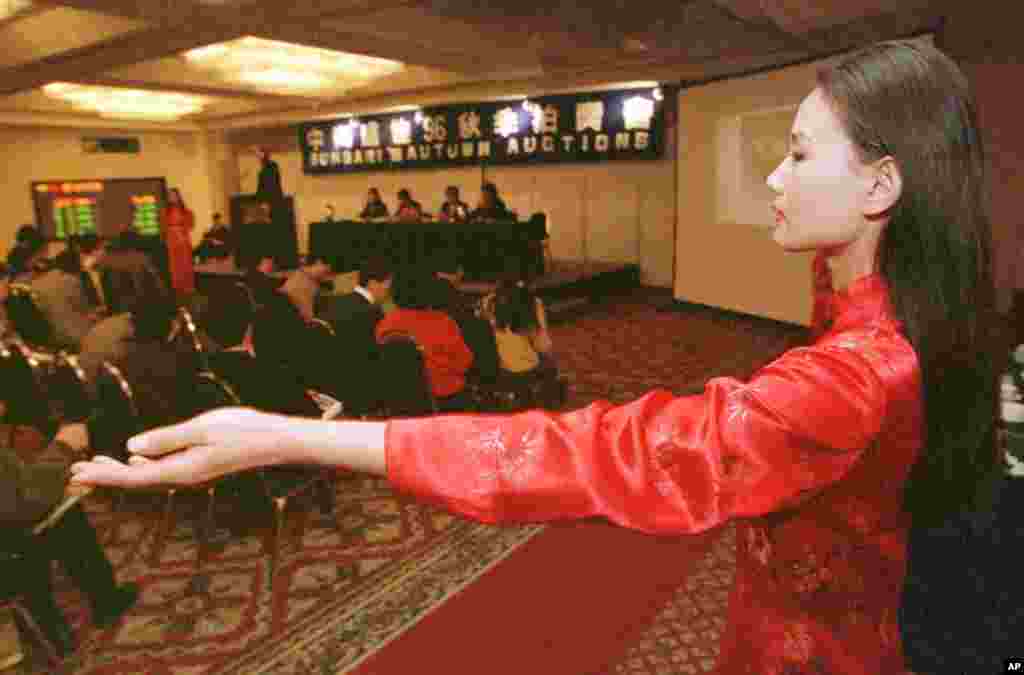 1996年11月12日,在王光美物品拍卖会上,一位助理用手指向一位竞购者。王光美从事慈善事业,拍卖家传珍品,得款全部捐给“幸福工程”。