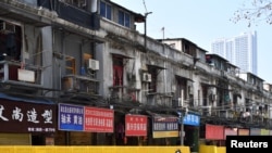 一名戴着口罩的骑车男子在武汉街头被封堵的商店旁驶过。(2020年3月5日)