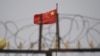 中国新疆地区喀什南部的一个住宅区外,铁丝网后面能看到高挂的中国国旗。(2019年6月4日)