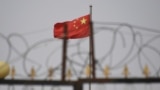 中国新疆地区喀什南部的一个住宅区外，铁丝网后面能看到高挂的中国国旗。（2019年6月4日）