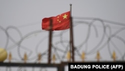 中国新疆地区喀什南部的一个住宅区外,铁丝网后面能看到高挂的中国国旗。(2019年6月4日)