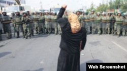 资料照:一名新疆维吾尔妇女举拳向一队中国武警士兵表示抗议。(照片来自世界维吾尔代表大会网站)