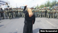 资料照:一名新疆维吾尔妇女举拳向一队中国武警士兵表示抗议。(照片来自世界维吾尔代表大会网站)